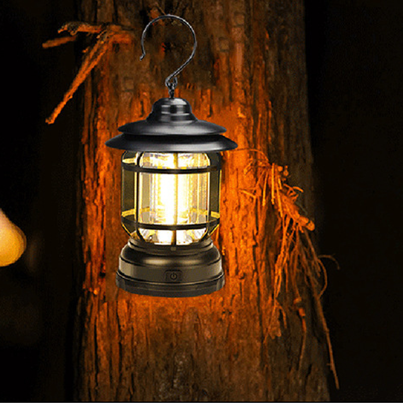 Svart retro LED-lykta hängande på trädstam i nattskogen