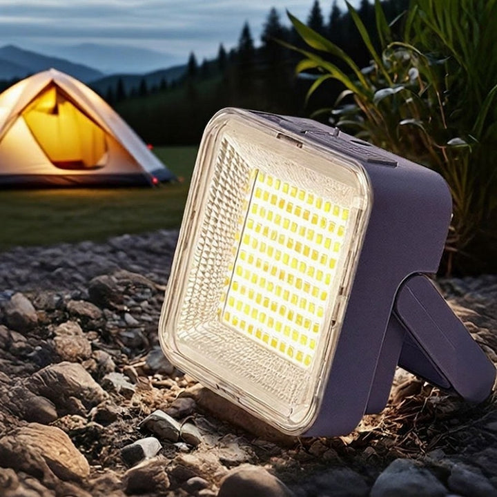 Campinglampa med tält i bakgrunden vid skymning